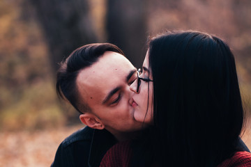 young man and young woman are sitting on a plaid in an autumn forest