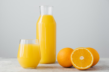 Glasses of orange juice, sliced fresh oranges on white background. Horizontal composition. Delicious fruit and drink. Citrus around