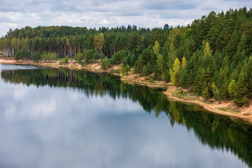 Fototapeta na wymiar calm countryside lake river with cloud reflections in water and green shores