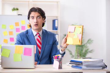 Young male handsome employee in conflicting priorities concept 