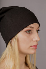 Portrait of a beautiful young girl in a stylish headdress with natural makeup on a gray background.