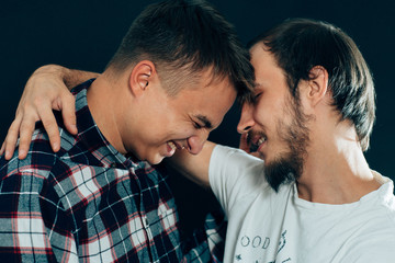 two guys hugging on a dark background