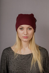 Portrait of a beautiful young girl in a stylish headdress with natural makeup on a gray background.