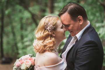 Fototapeta premium bride and groom kissing in the summer forest