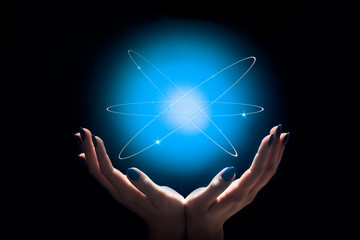 woman's hands hold a bright glowing sphere, the universe, the whole world, the atom in the hands,...