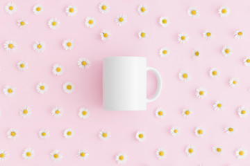 Top view of a white mug mockup with daisy decoration on a pink background.