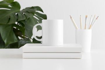 Mug mockup with workspace accessories and a monstera plant.