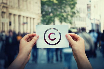 Hands hold paper with copyright symbol. International legal rights intellectual property sign,...
