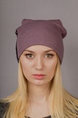 Portrait of a beautiful young girl in a stylish headdress with natural makeup on a gray background.