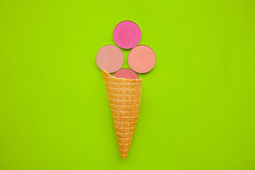 The concept of beauty and fashion. round pink blush in a cone for ice cream on a green background