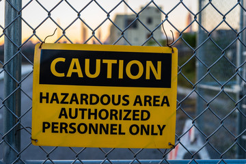 Caution sign for hazardous area on metal fence