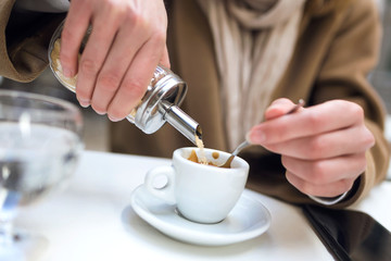 Woman's hand pouring sugar into the cup of coffee.
