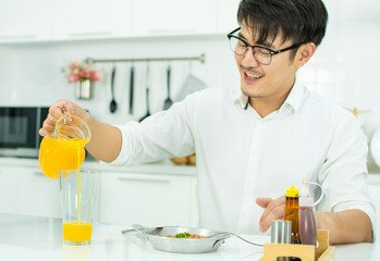 A handsome is pouring the orange juice to the glass