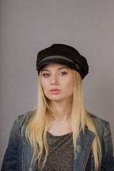 Portrait of a beautiful young girl in a stylish headdress with natural makeup on a gray background.