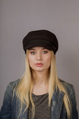 Portrait of a beautiful young girl in a stylish headdress with natural makeup on a gray background.