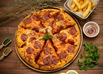 Homemade pepporoni pizza with the ingredients, put on the wooden table