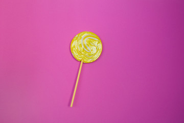 Yellow lollipop on delicate pink background