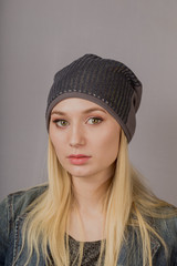 Portrait of a beautiful young girl in a stylish headdress with natural makeup on a gray background.