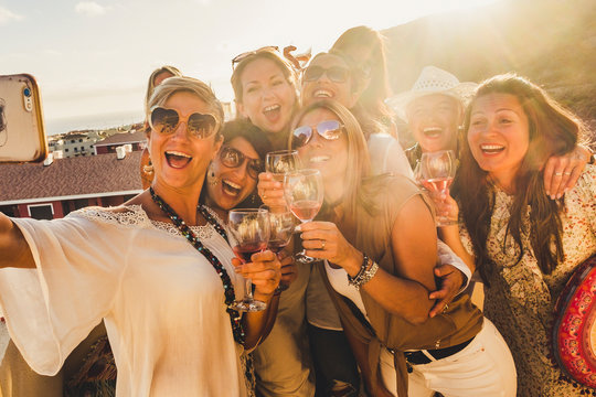 Happiness Concept For Caucasian Young Women Friends Laugh And Have Fun Together In Friendship Taking A Selfie Picture With A Smartphone - Sun In Backlight And View