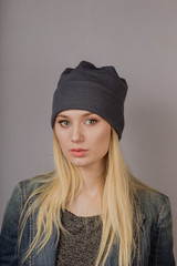 Portrait of a beautiful young girl in a stylish headdress with natural makeup on a gray background.