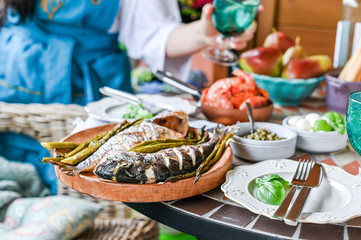 Woman with a glass in her hands. Dining table with different food and snacks. Seafood and vegetables. Summer lunch in the open air.
