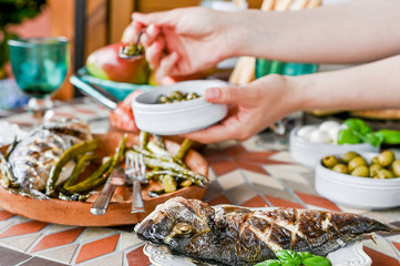 Woman with a plate in her hands. Dining table with different food and snacks. Seafood and vegetables. Summer lunch in the open air.