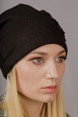 Portrait of a beautiful young girl in a stylish headdress with natural makeup on a gray background.