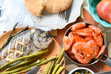 Shrimp in a pan. Dining table with different foods, snacks and flowers. Summer lunch in the open air. Seafood and asparagus.
