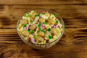 Potato salad with marinated mushrooms, sausage, onion and mayonnaise on wooden table