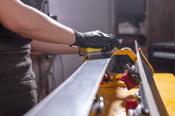 Work and repair concept - a man's hands repairing the ski by rubbing a paraffin