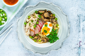 Ramen noodles with chicken, egg, mushrooms and radish sprinkeld with chili sauce and sesame seeds - top view
