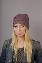 Portrait of a beautiful young girl in a stylish headdress with natural makeup on a gray background.