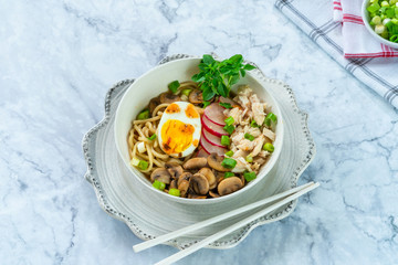 Ramen noodles with chicken, egg, mushrooms and radish sprinkeld with chili sauce and sesame seeds - high angle view