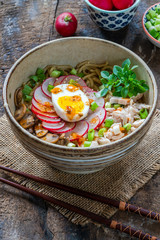 Ramen noodles with chicken, egg, mushrooms and radish sprinkeld with chili sauce and sesame seeds - high angle view