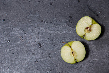 the photo shows green, juicy, fresh apples lying on a dark marble table