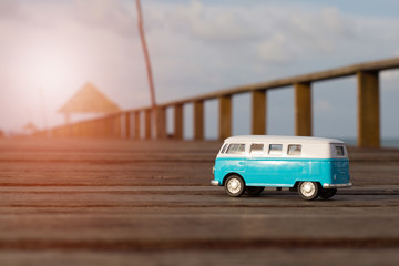 Blue van on wood bridge with sea background.