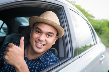 Young asian man showing thumbs up while driving car with copy space.
