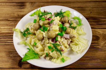Potato salad with marinated mushrooms, eggs, red onion and mayonnaise on wooden table