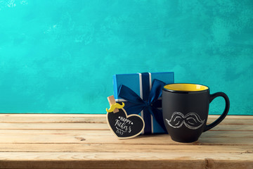 Happy Father's day concept with coffee mug and gift box over wooden background