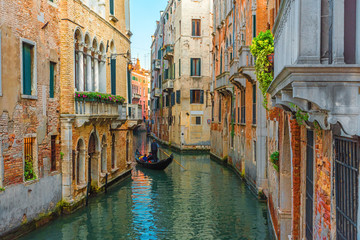 Fototapeta na wymiar Venice, Italy. Venetian gondolier floating on gondola with tourists through green canal waters of Venice
