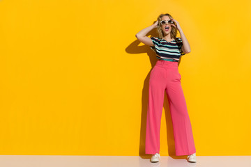 Happy Stylish Woman In Sunglasses, Pink Wide Legs Trousers, Sneakers And Striped Blouse Is Shouting