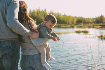 Happy family with Cute baby boy on the lake water background outdoors, sensitivity to the nature...