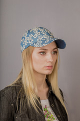 Portrait of a beautiful young girl in a stylish headdress with natural makeup on a gray background.