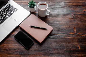 work space of a businessman. view from above . coffee black note and laptop on the desktop with black note. laptop on wooden background