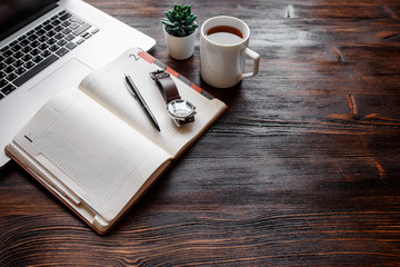 work space of a businessman. view from above . coffee black note and laptop on the desktop with black note. laptop on wooden background