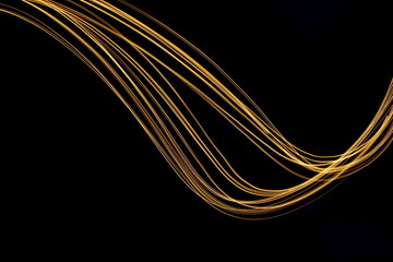 Long exposure, light painting photography.  Vibrant streaks of metallic gold colour against a black background