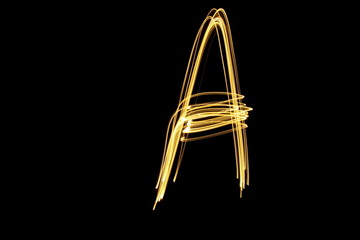 Long exposure, light painting photography.  Single letter a in a vibrant neon metallic yellow gold colour against a black background.  Alphabet series.