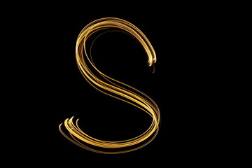 Long exposure, light painting photography.  Single letter S in a vibrant neon metallic yellow gold colour against a black background.  Alphabet series.