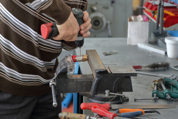 Handyman handles part in cast-iron vice in repair shop