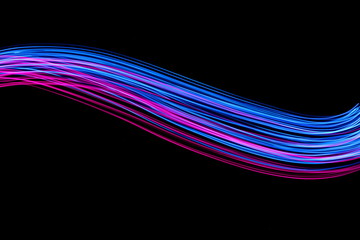 Long exposure, light painting photography.  Vibrant electric blue and neon pink streaks of colour against a black background